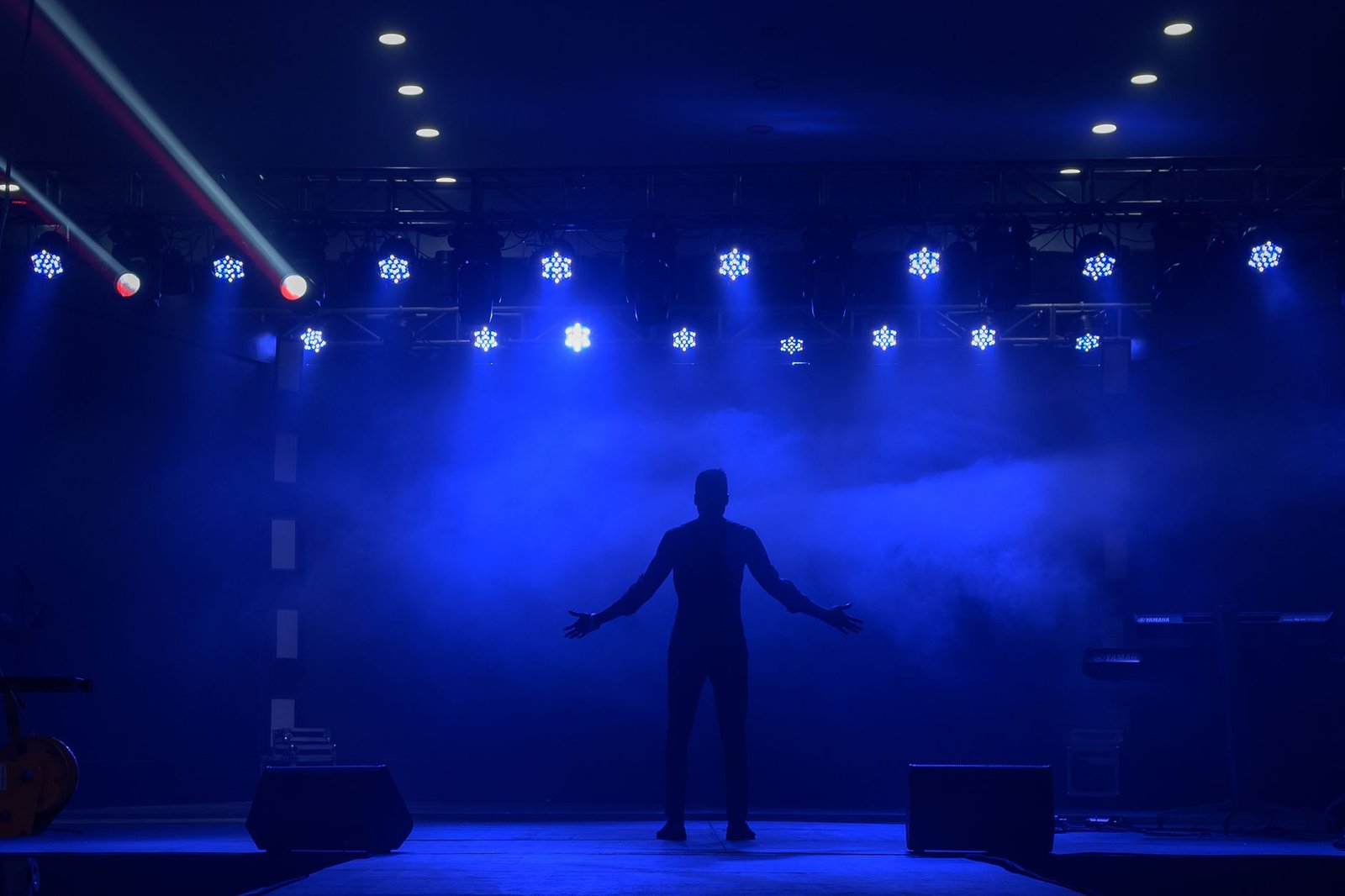 silhouette of a keynote speaker standing on a dramatic blue lit stage representing the goal of building a professional speaking career