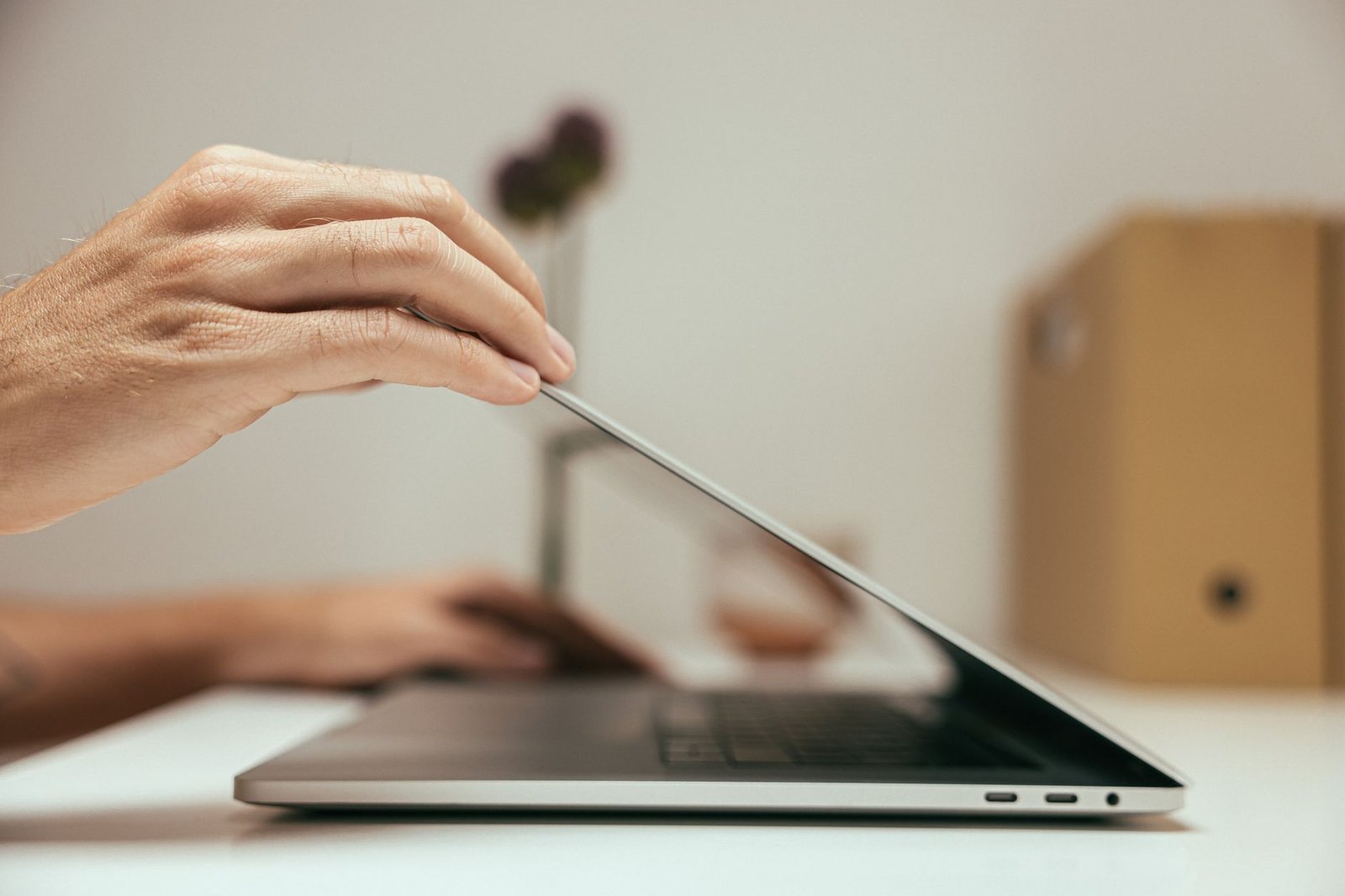 hand closing laptop in minimal clean office setting representing an event organizer moving on from a speaker website
