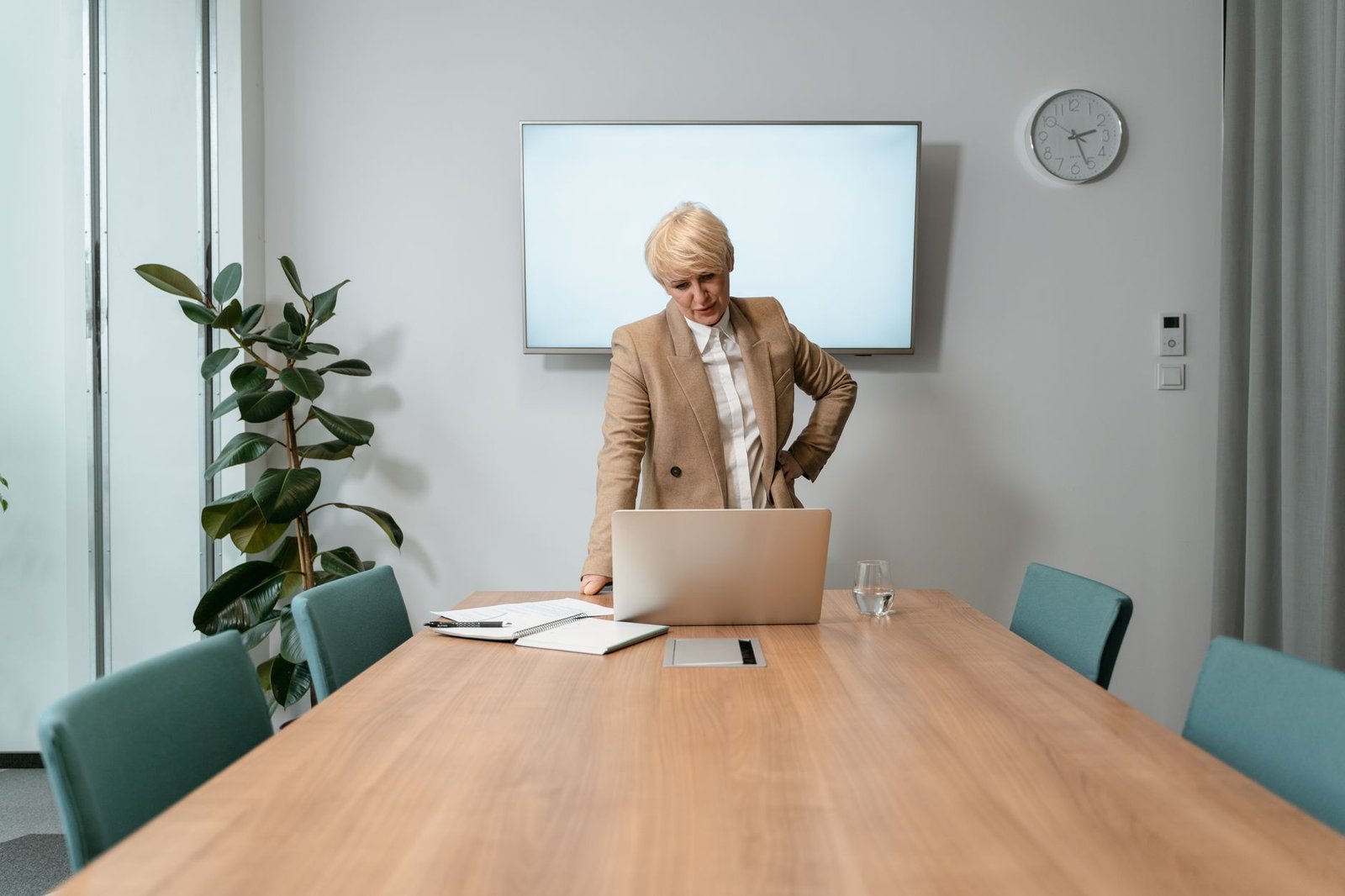 professional event organizer in corporate boardroom evaluating a keynote speaker website on laptop