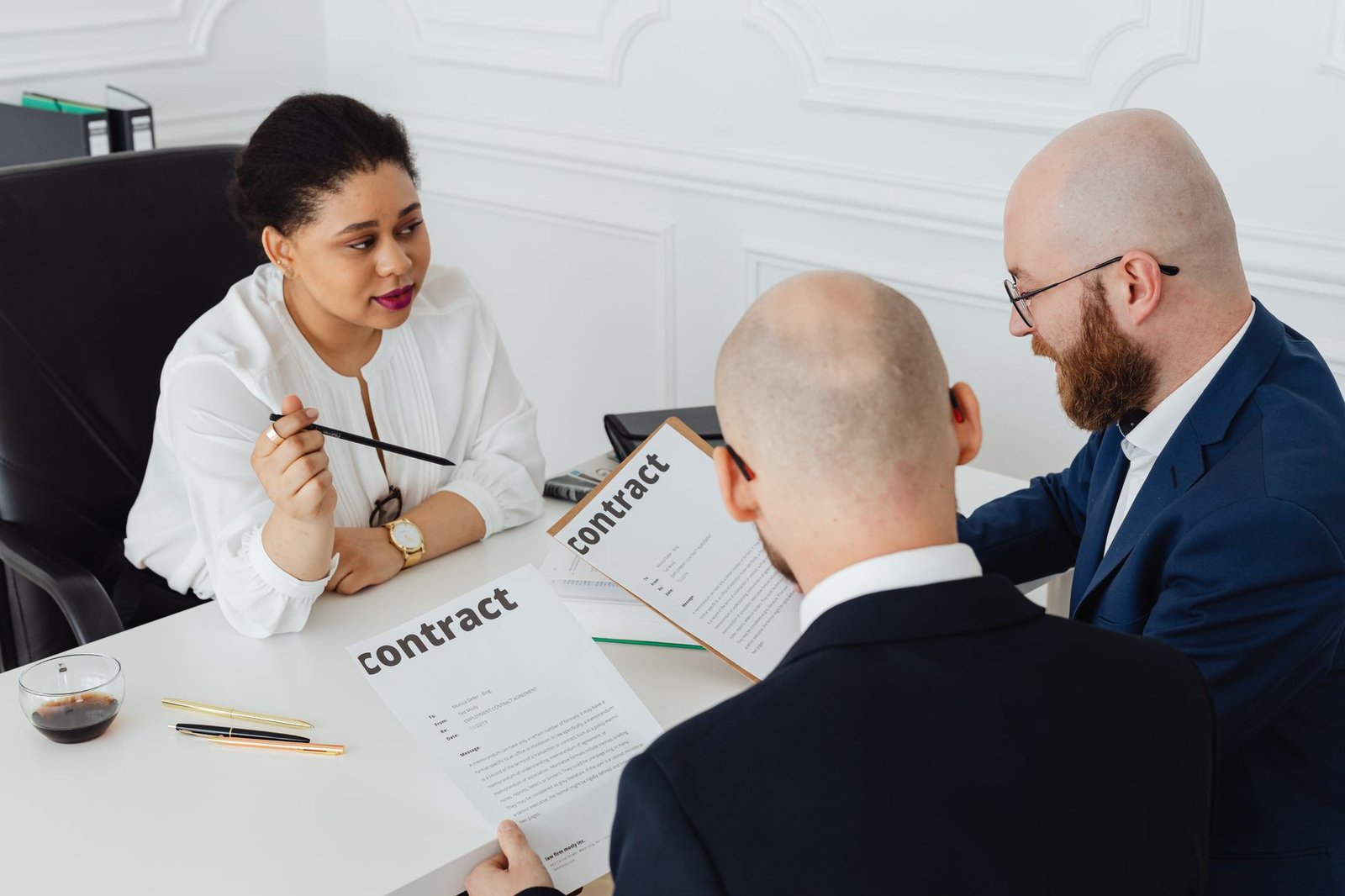 three business professionals discussing a speaking fee contract in a modern office setting