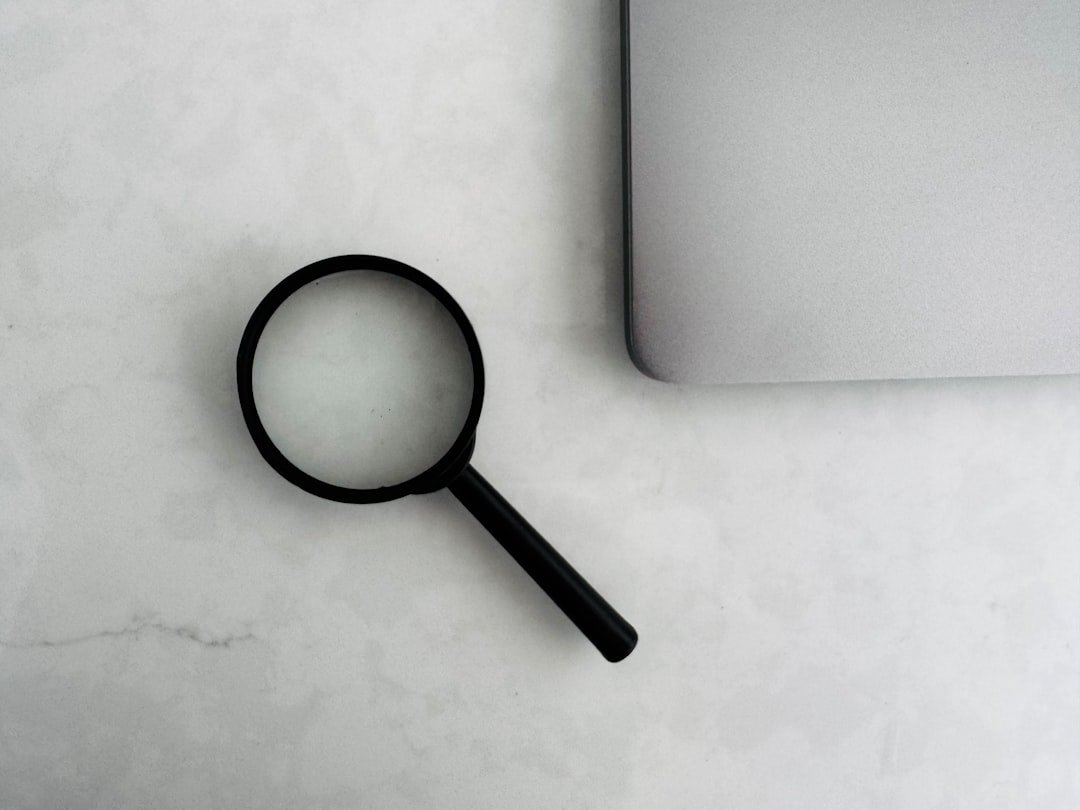 magnifying glass beside laptop representing keynote speaker website SEO and search engine discovery