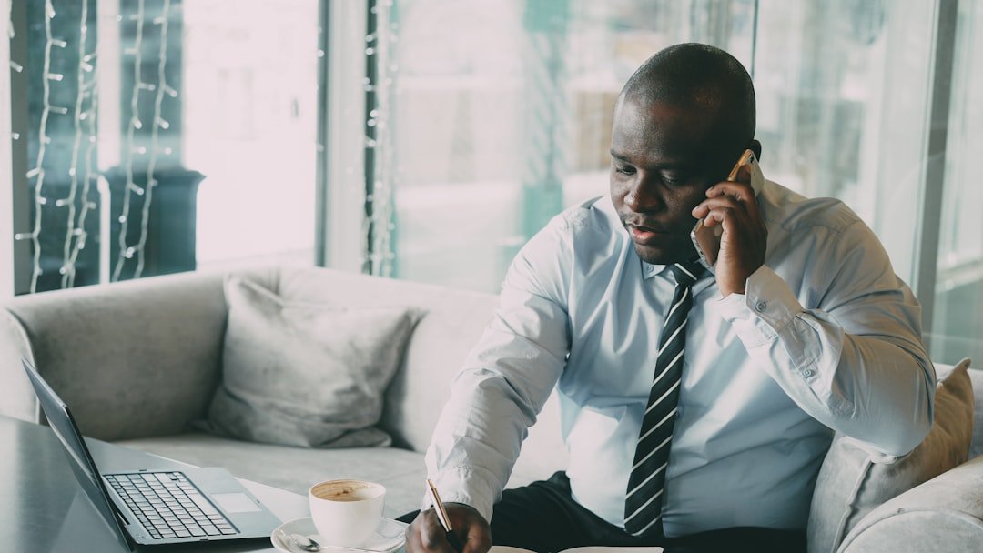 confident businessman making professional outreach phone call for speaking opportunities while taking notes in notebook