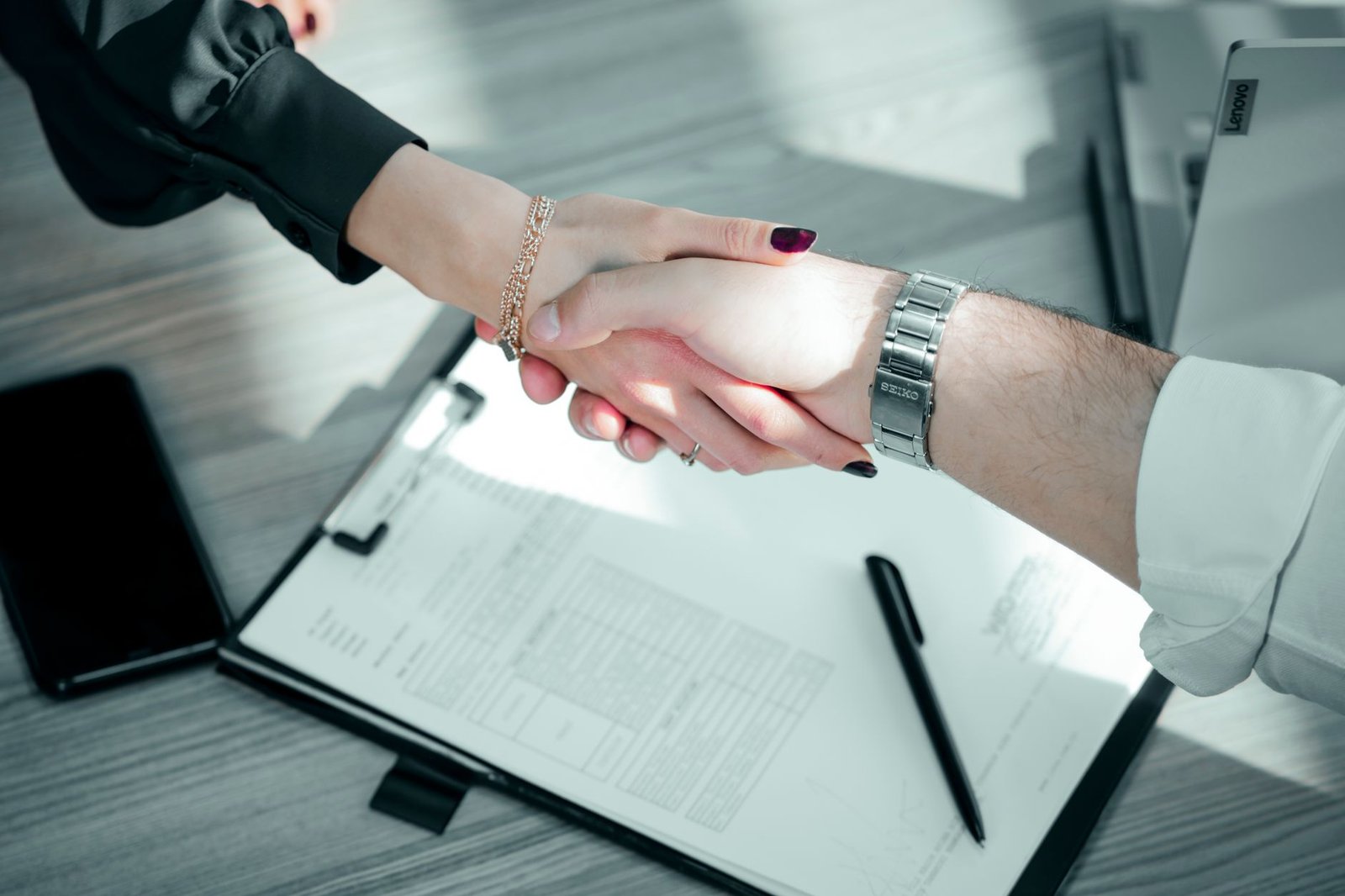 professional handshake over signed contract representing a finalized keynote speaker fee agreement