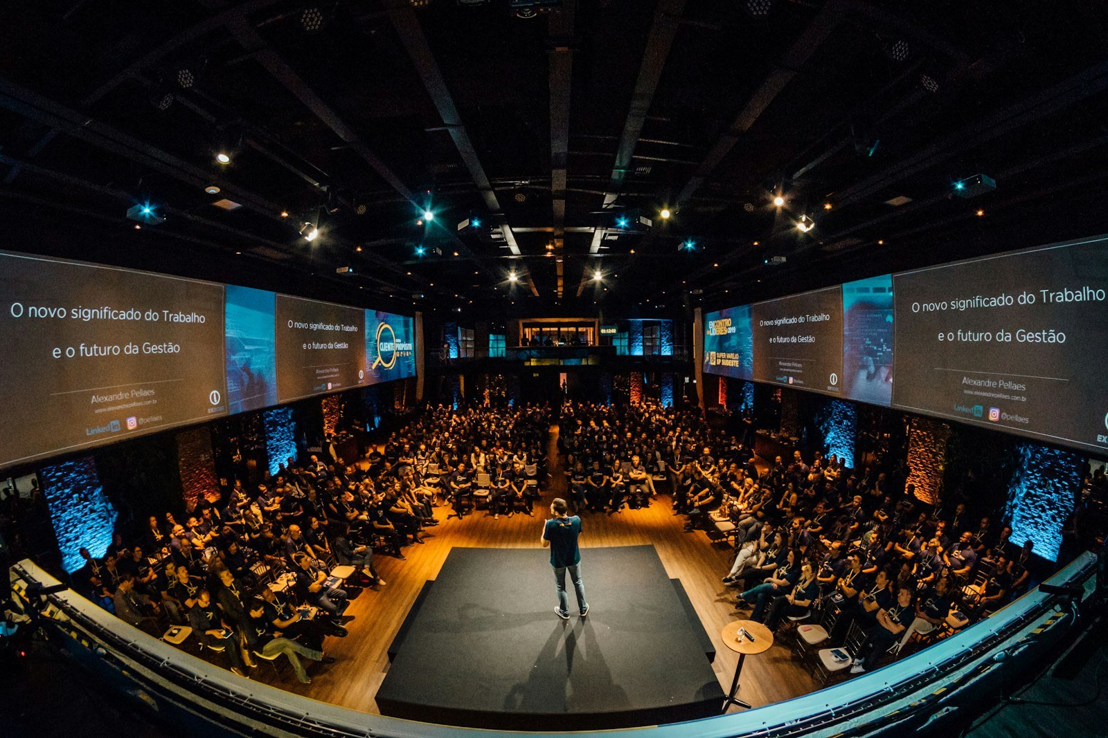 keynote speaker on stage addressing a large packed conference audience
