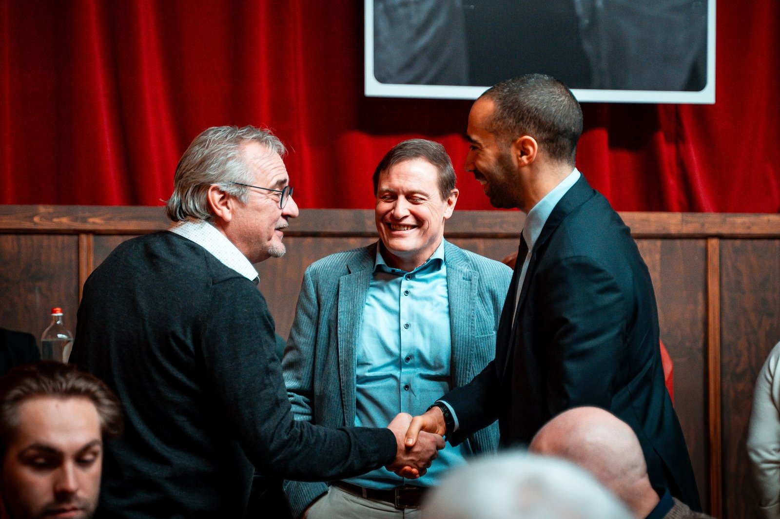professional speakers networking and shaking hands at business conference representing getting more speaking gigs