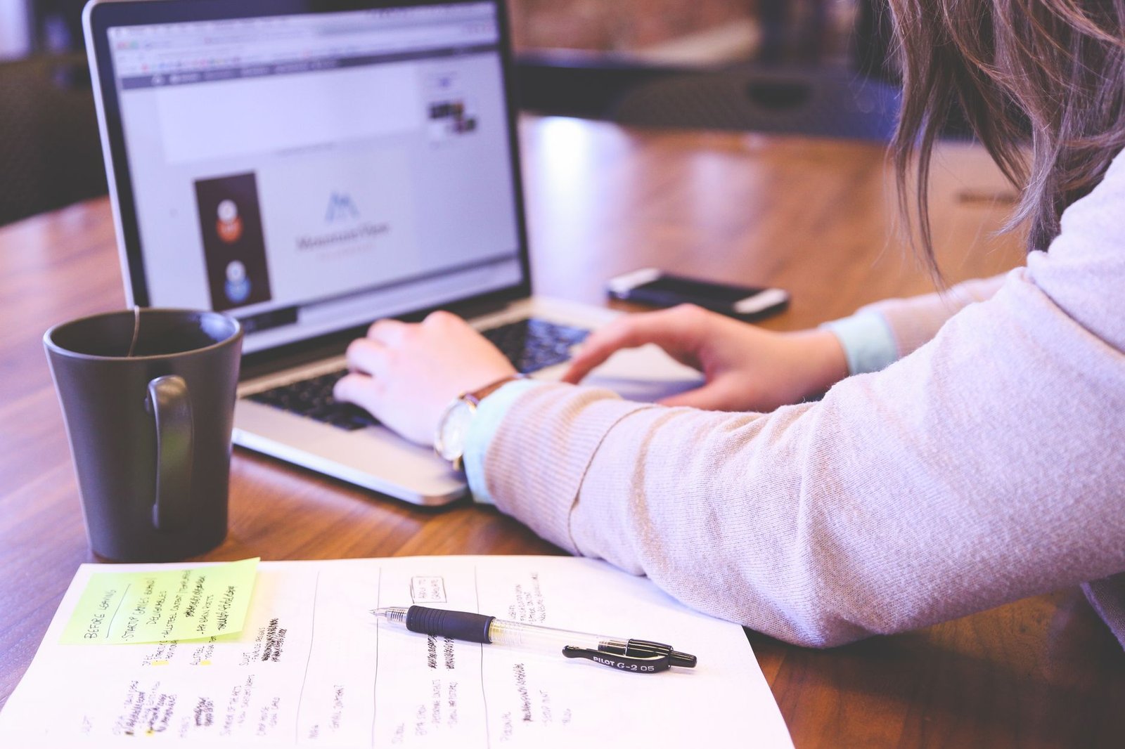 businesswoman planning website redesign with laptop and notes representing a coach repositioning their website for keynote speaking