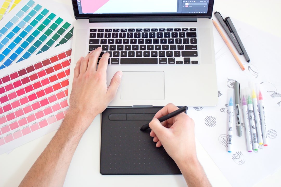 graphic designer working on laptop with color charts selecting typography for a keynote speaker website design