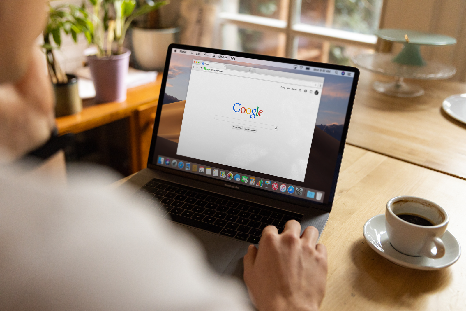 event organizer browsing Google on laptop at wooden table representing what organizers type into search before booking a keynote speaker