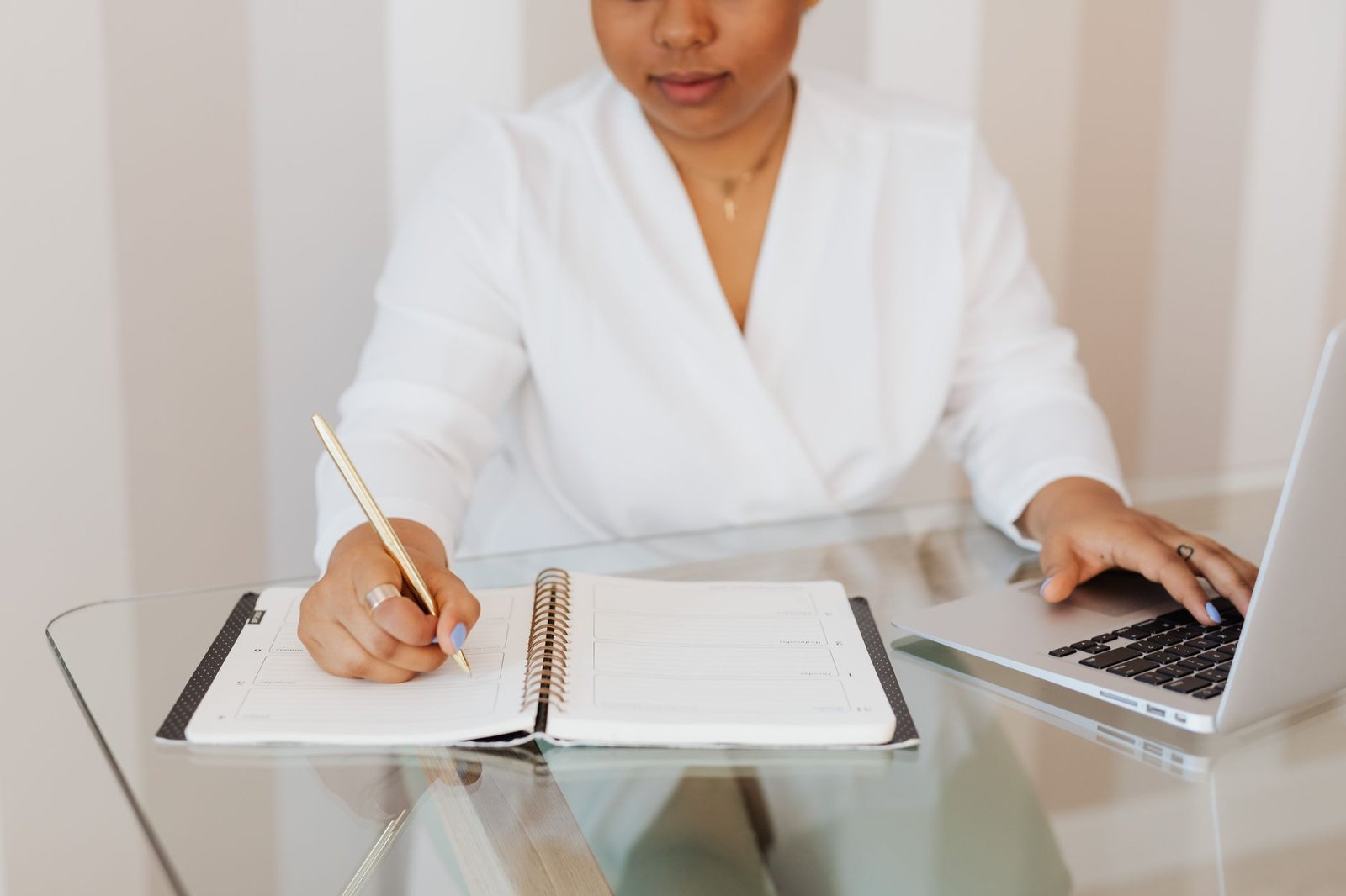 event planner at desk with notebook and laptop verifying a keynote speaker shortlist during the verification stage