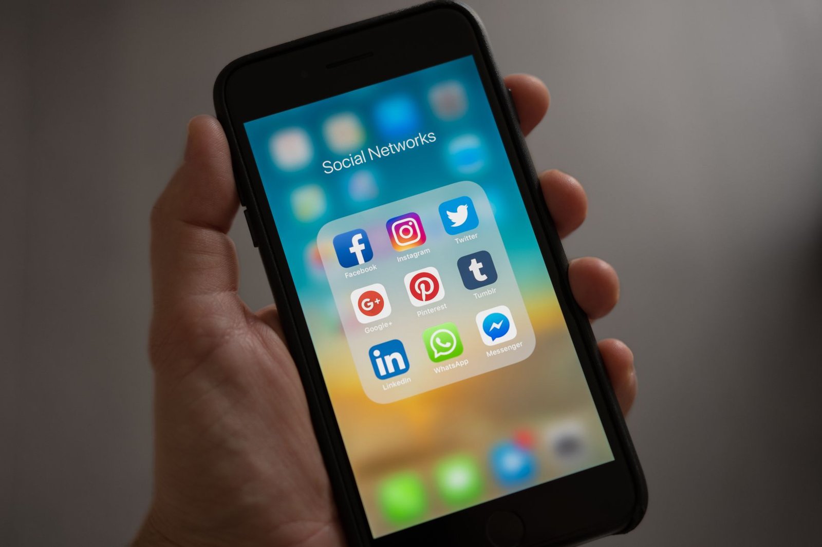 hand holding a smartphone displaying social media app icons representing LinkedIn and Medium as rented platforms a speaker does not control