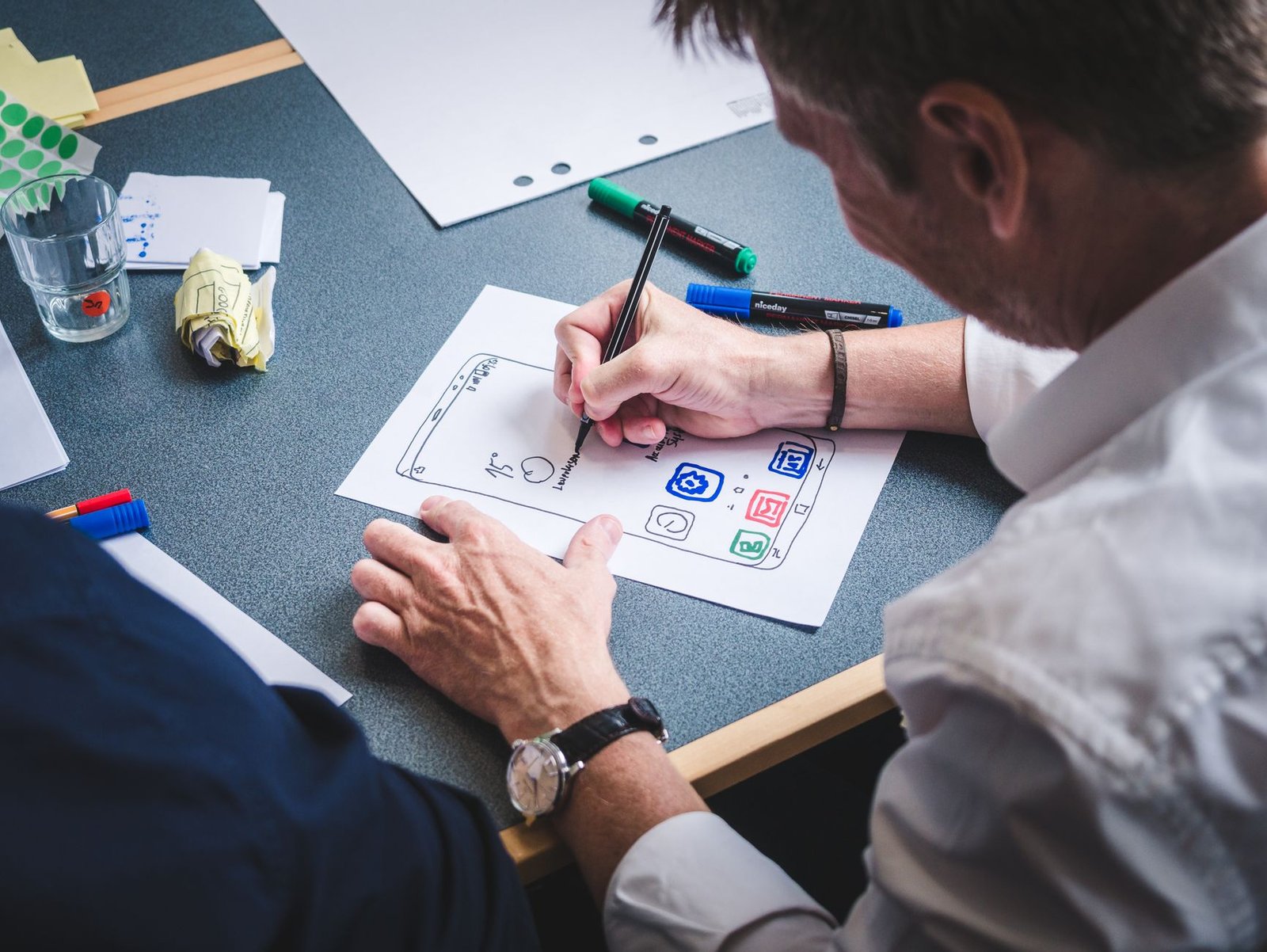 designer sketching a mobile app prototype on paper representing the wireframe planning behind a high-converting speaker homepage