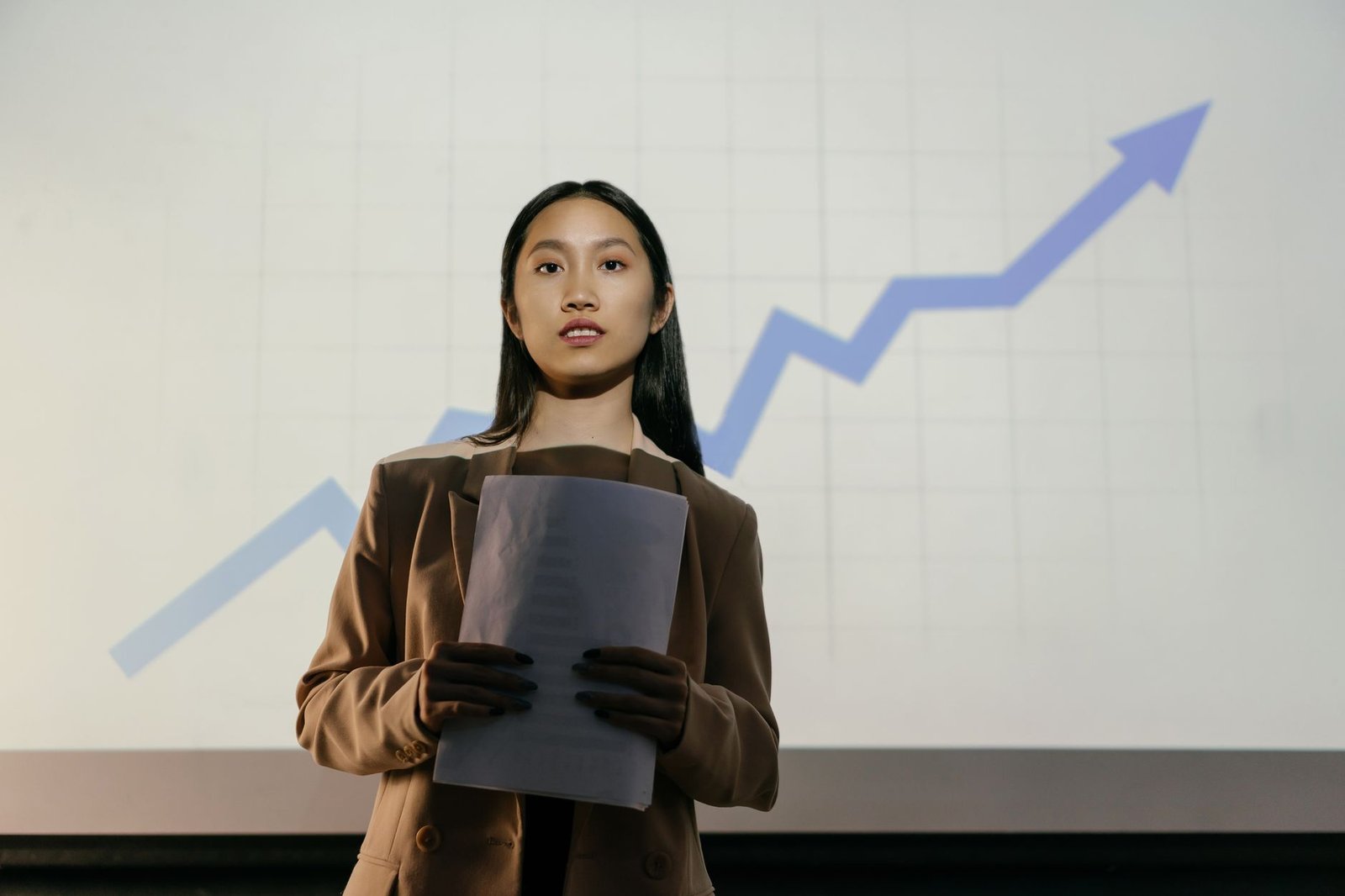 confident businesswoman presenting a growth chart representing a keynote speaker who invests in their business and gets booked faster