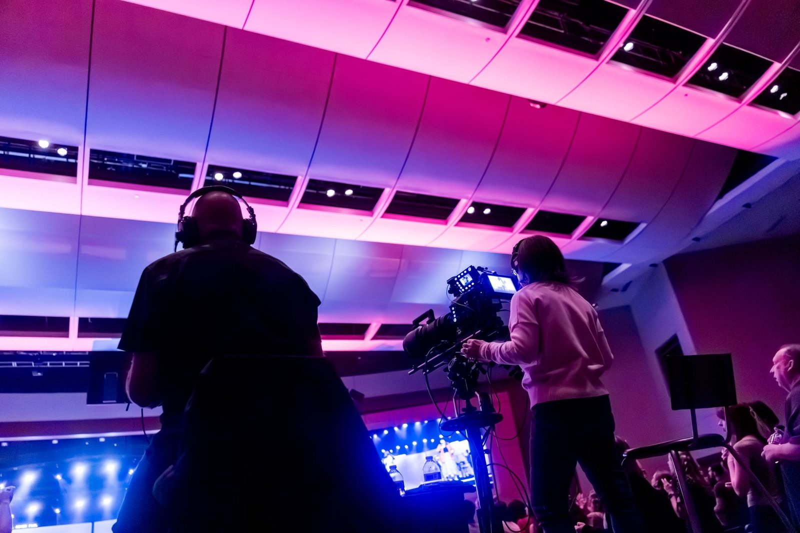 professional camera crew filming a speaker on stage with vibrant lighting representing the footage that becomes a speaker reel organizers watch before booking