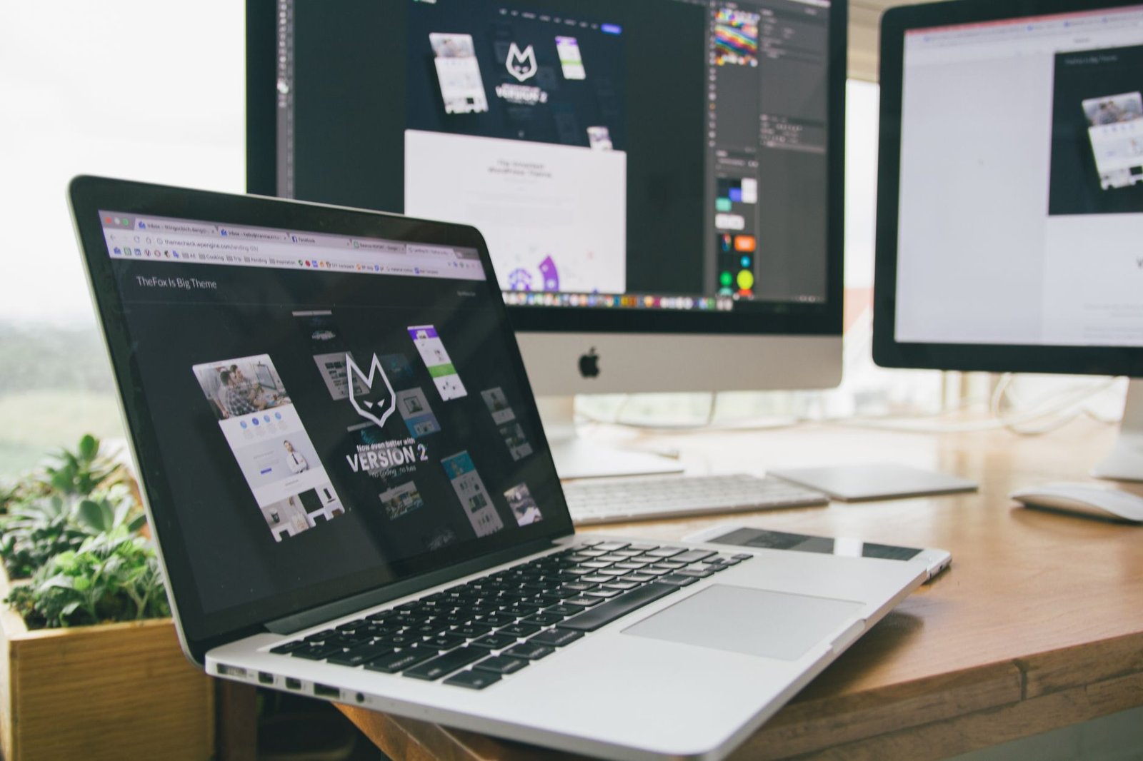 modern workspace with laptop and monitors displaying design software representing a fully built keynote speaker website structure