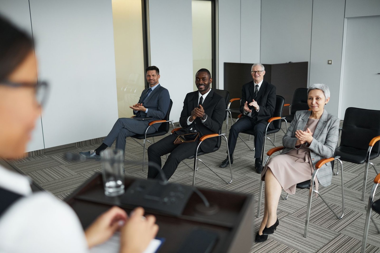 diverse group of business professionals applauding in conference room representing the keynote speaker who won the booking